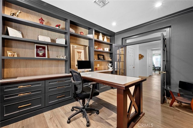 home office featuring crown molding, light hardwood / wood-style flooring, and built in shelves