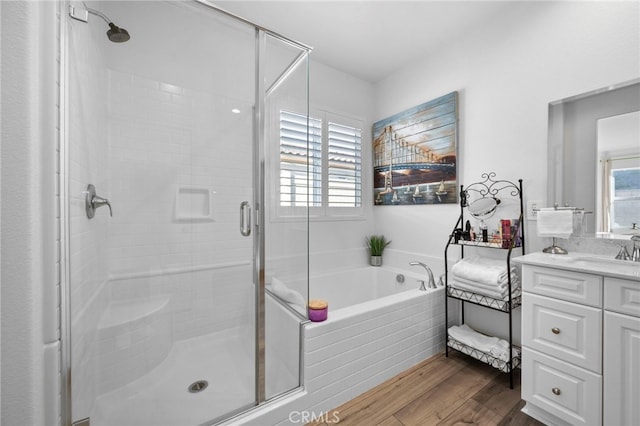 bathroom with independent shower and bath, vanity, a healthy amount of sunlight, and hardwood / wood-style floors