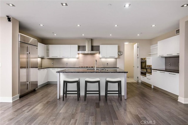 kitchen with dark hardwood / wood-style flooring, white cabinetry, stainless steel appliances, and exhaust hood