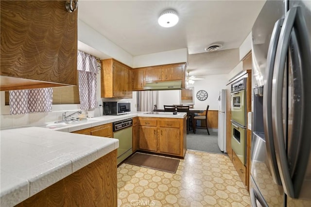 kitchen featuring sink, ceiling fan, appliances with stainless steel finishes, tile counters, and kitchen peninsula