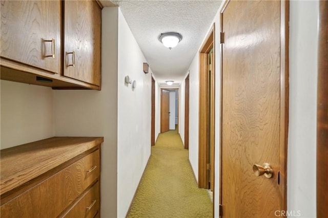 corridor with light colored carpet and a textured ceiling