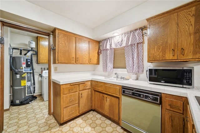 kitchen featuring sink, dishwasher, strapped water heater, washer / clothes dryer, and tile countertops