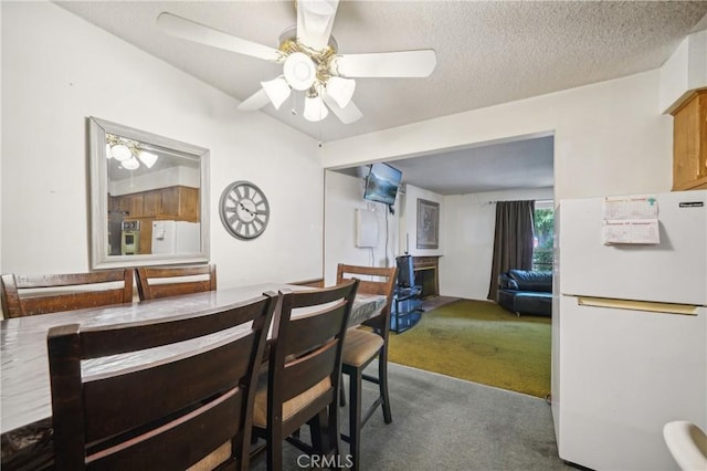 carpeted dining room featuring ceiling fan and a textured ceiling