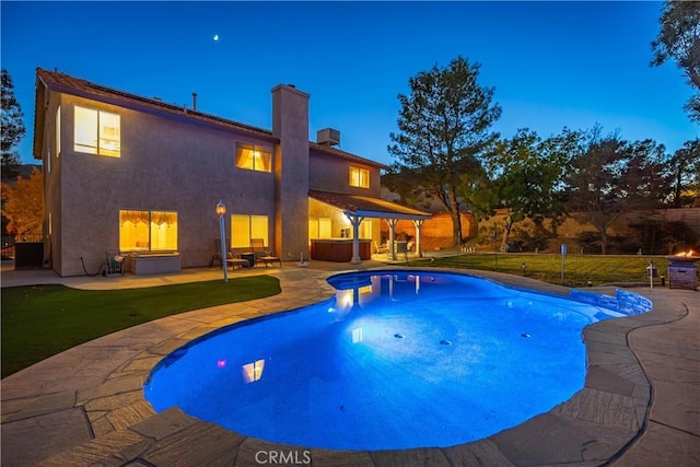 pool at dusk featuring a lawn and a patio