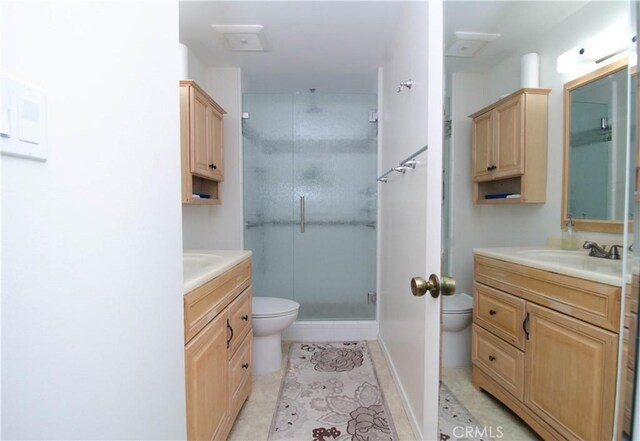 bathroom featuring toilet, vanity, tile patterned flooring, and a shower with shower door