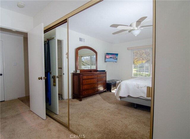 bedroom featuring ceiling fan, light colored carpet, and a closet