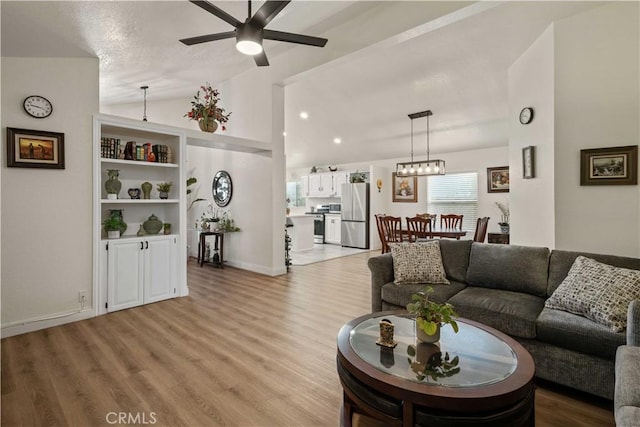 living room featuring built in features, light hardwood / wood-style flooring, ceiling fan, and lofted ceiling