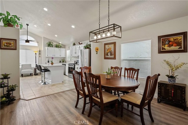 dining area featuring ceiling fan, light hardwood / wood-style flooring, and vaulted ceiling