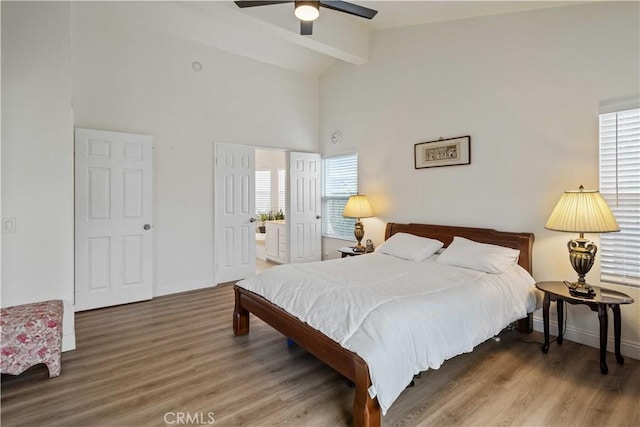 bedroom with dark hardwood / wood-style floors, ceiling fan, beam ceiling, and connected bathroom