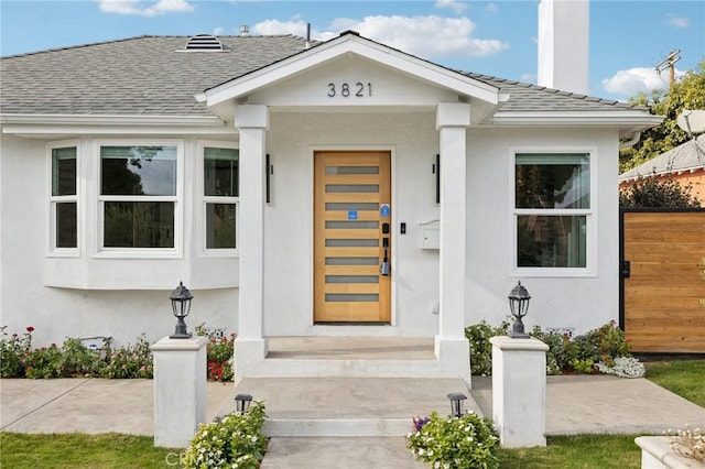 3821 S Muirfield Rd, Los Angeles, CA 90008 - property entrance with roof with shingles, stucco siding, and a chimney