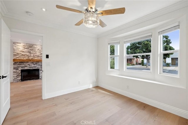 unfurnished room with a fireplace, light hardwood / wood-style floors, ceiling fan, and ornamental molding