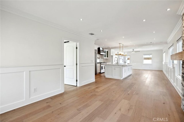 unfurnished living room with a stone fireplace, ceiling fan, light wood-type flooring, and ornamental molding