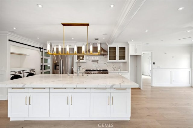 kitchen with a barn door, white cabinetry, and independent washer and dryer