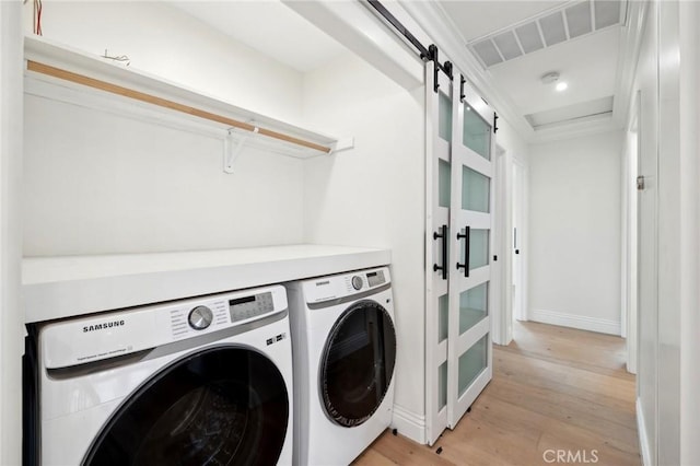 washroom featuring a barn door, light hardwood / wood-style flooring, and washing machine and dryer