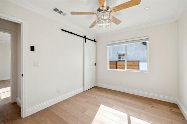 unfurnished bedroom featuring light wood-type flooring, a barn door, ceiling fan, and ornamental molding