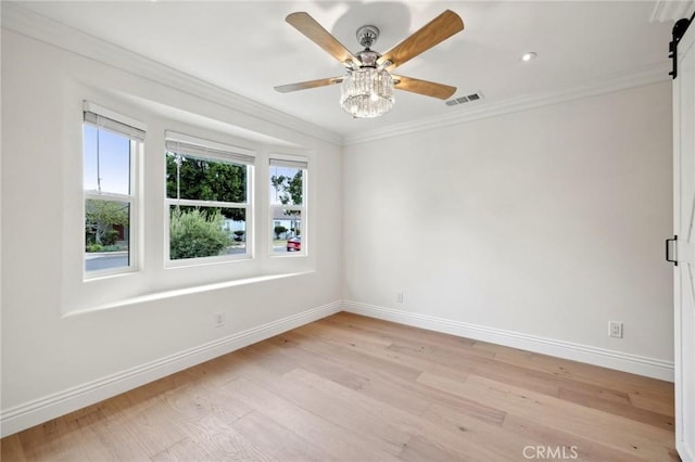 unfurnished room featuring a barn door, ceiling fan, light hardwood / wood-style flooring, and ornamental molding