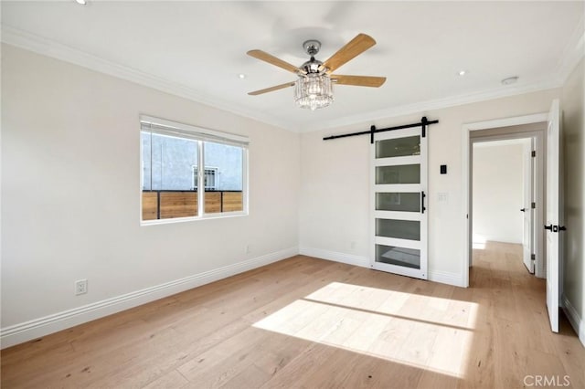 unfurnished bedroom featuring a barn door, light hardwood / wood-style floors, ceiling fan, and ornamental molding