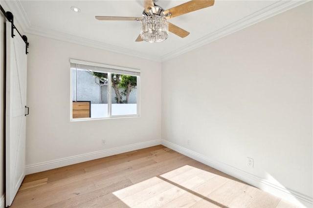 spare room with a barn door, ceiling fan, ornamental molding, and light wood-type flooring