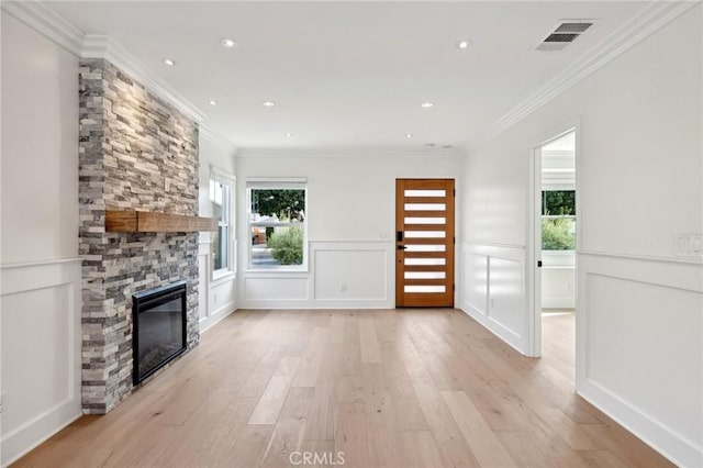 unfurnished living room featuring crown molding, a fireplace, and light hardwood / wood-style floors