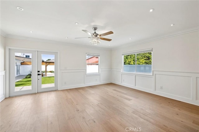 empty room with ceiling fan, crown molding, light hardwood / wood-style floors, and french doors