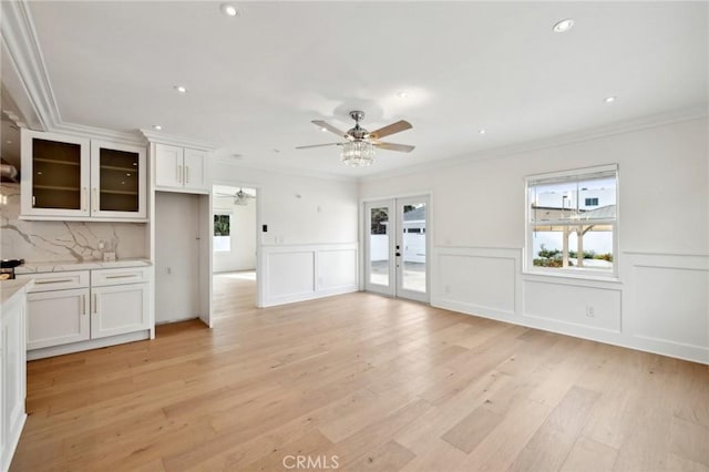 unfurnished living room with french doors, light hardwood / wood-style flooring, ceiling fan, and crown molding