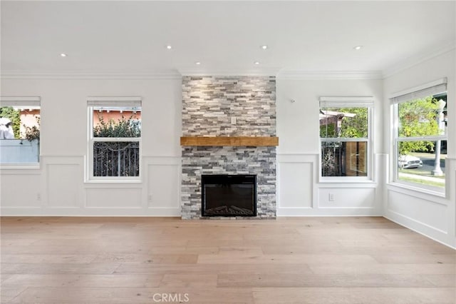 unfurnished living room with light hardwood / wood-style floors, crown molding, and a fireplace