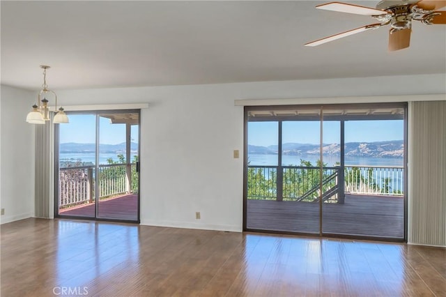 unfurnished room with hardwood / wood-style floors, ceiling fan with notable chandelier, and a water and mountain view