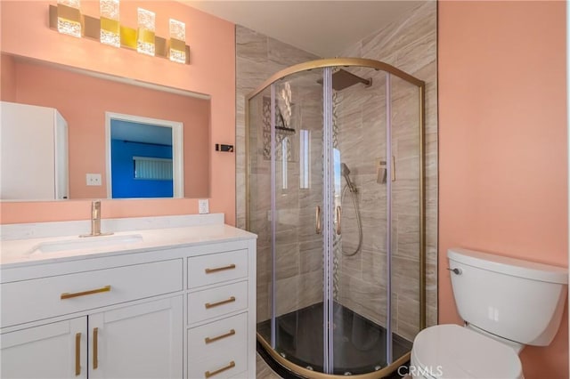 bathroom featuring vanity, toilet, and a shower with door