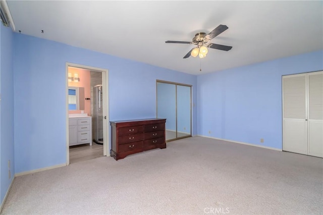 unfurnished bedroom featuring multiple closets, ensuite bathroom, ceiling fan, and light colored carpet