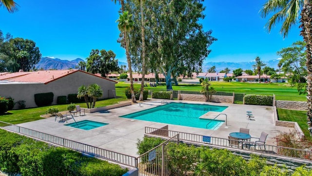 view of pool with a mountain view, a patio area, a hot tub, and a lawn