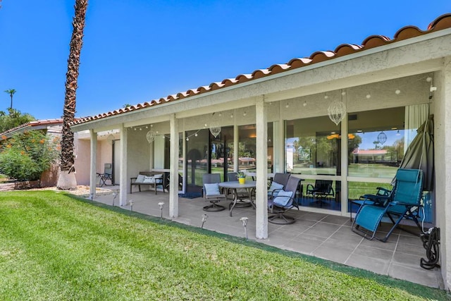 back of house with a patio and a lawn