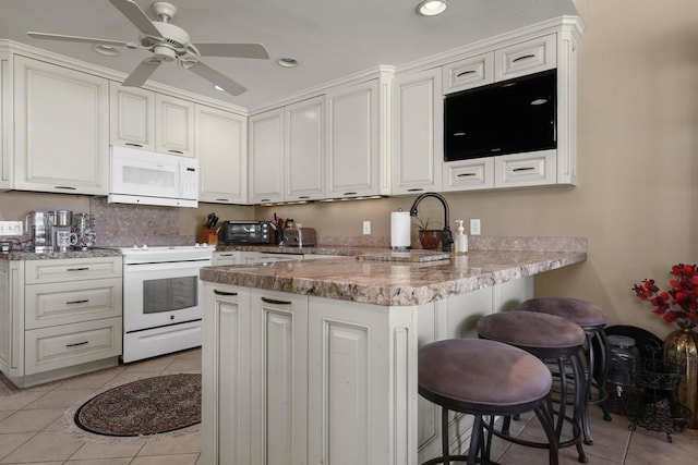 kitchen featuring white cabinetry, white appliances, and kitchen peninsula