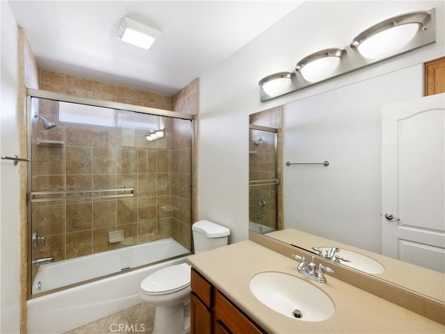 full bathroom with vanity, bath / shower combo with glass door, and toilet