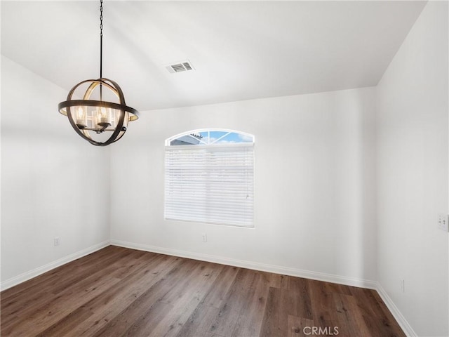 spare room featuring hardwood / wood-style floors and a chandelier