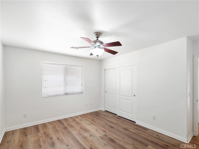 unfurnished bedroom with ceiling fan, wood-type flooring, and a closet