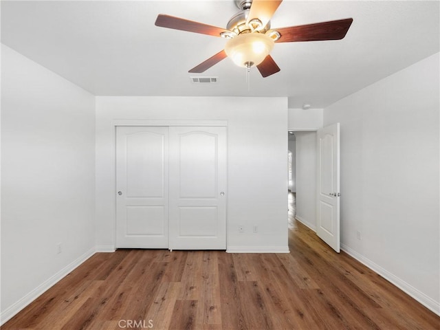 unfurnished bedroom featuring ceiling fan, a closet, and wood-type flooring