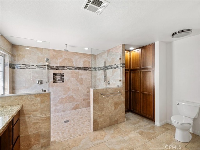 bathroom featuring tiled shower, vanity, and toilet