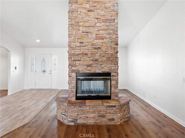 unfurnished living room with a stone fireplace and wood-type flooring