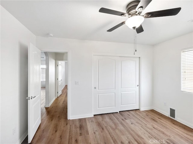 unfurnished bedroom featuring ceiling fan, light hardwood / wood-style floors, and a closet