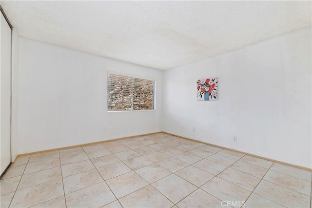 tiled spare room featuring a textured ceiling