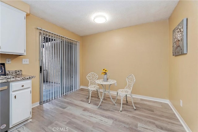 dining area with light hardwood / wood-style floors and a textured ceiling