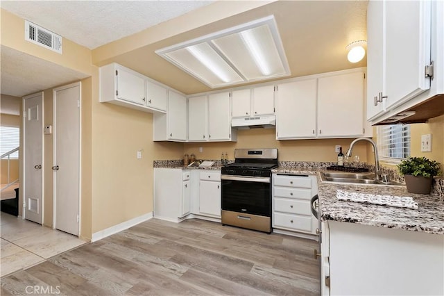 kitchen with stainless steel gas stove, light hardwood / wood-style flooring, white cabinetry, and sink