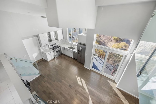 kitchen featuring sink, stainless steel appliances, a high ceiling, dark hardwood / wood-style flooring, and white cabinets