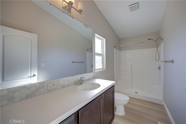 bathroom featuring a shower, vaulted ceiling, toilet, vanity, and hardwood / wood-style flooring