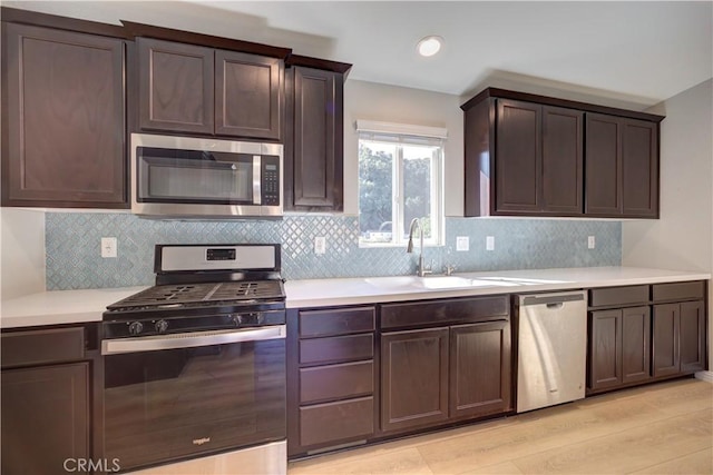 kitchen with sink, light hardwood / wood-style flooring, dark brown cabinets, and appliances with stainless steel finishes