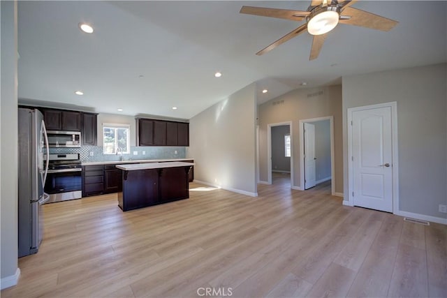 kitchen featuring vaulted ceiling, light hardwood / wood-style flooring, dark brown cabinets, a kitchen island, and stainless steel appliances