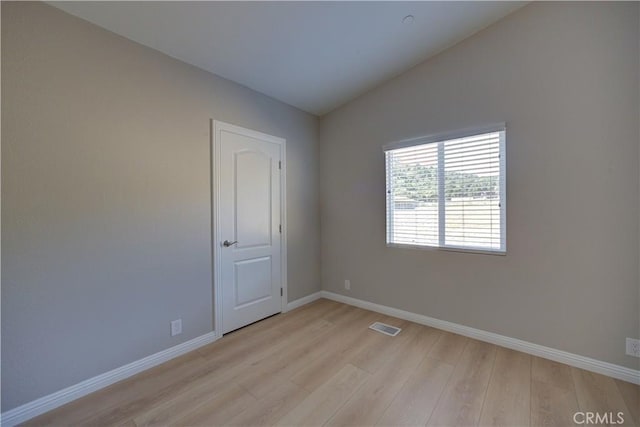 unfurnished room with light wood-type flooring and vaulted ceiling