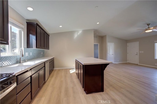 kitchen featuring light wood-type flooring, backsplash, a breakfast bar, dishwasher, and a kitchen island