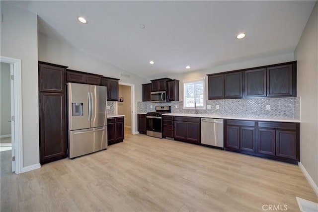 kitchen with dark brown cabinetry, light wood-type flooring, vaulted ceiling, and appliances with stainless steel finishes