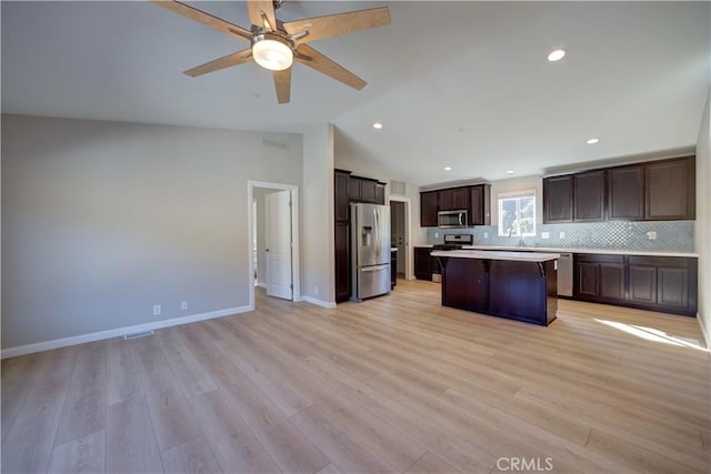 kitchen with ceiling fan, a center island, stainless steel appliances, light hardwood / wood-style flooring, and lofted ceiling